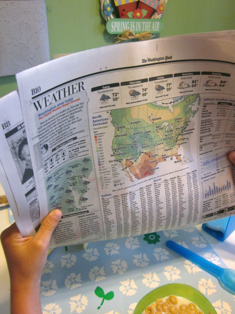 child holding weather section of newspaper