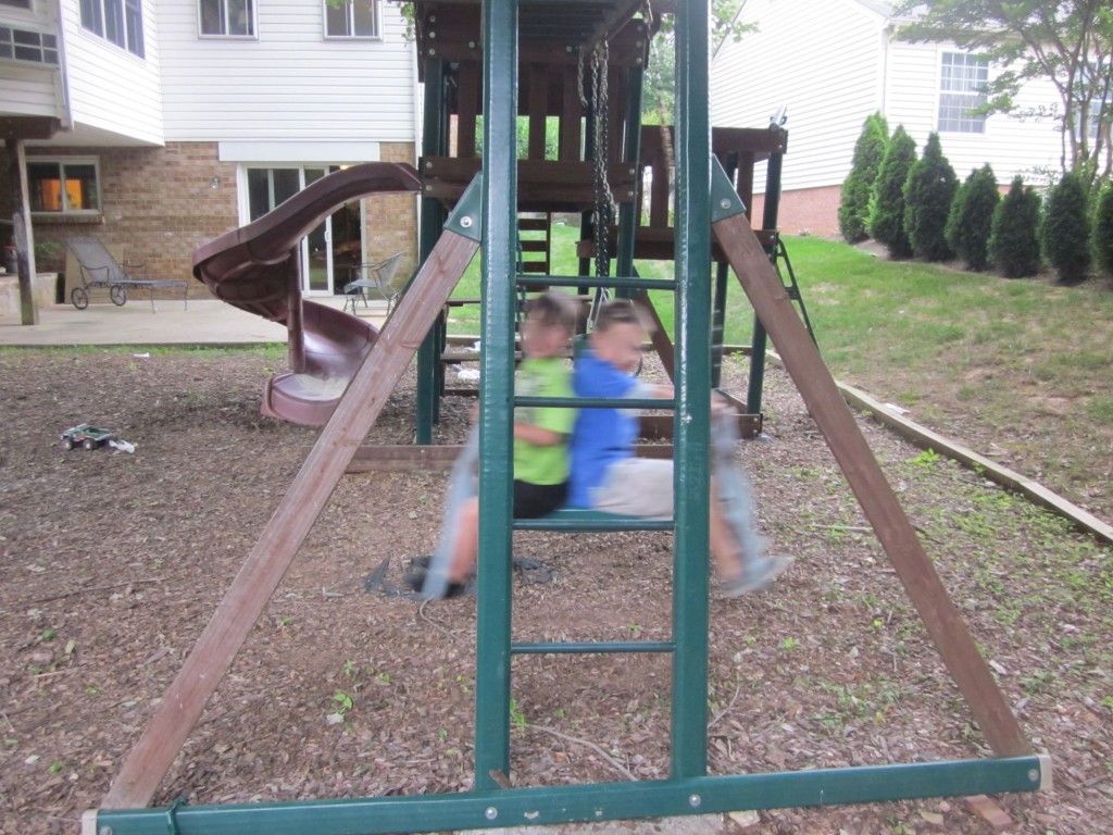 little kids swinging on swings on backyard playset
