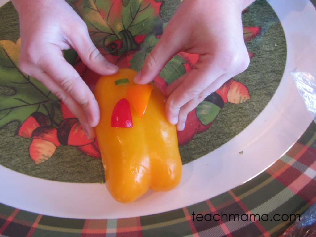 girl's hands adding orange pepper beak to yellow pepper body