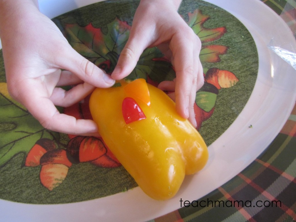 girl's hands adding green pepper eyes to yellow pepper