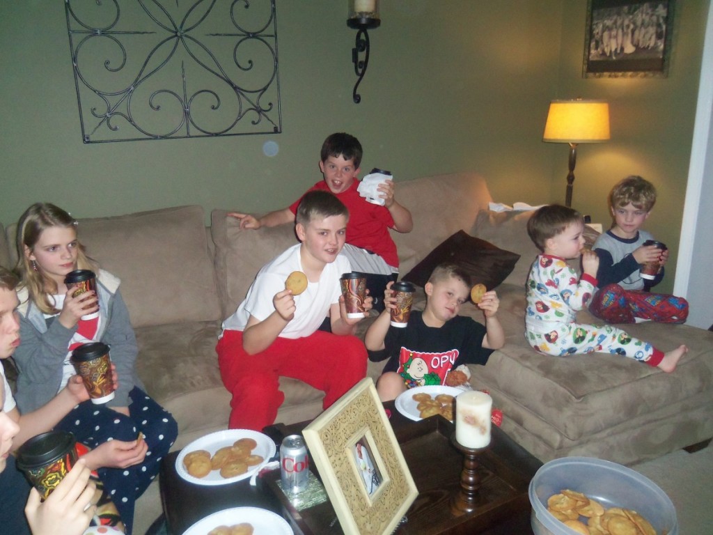 children holding hot cocoa and watching tv