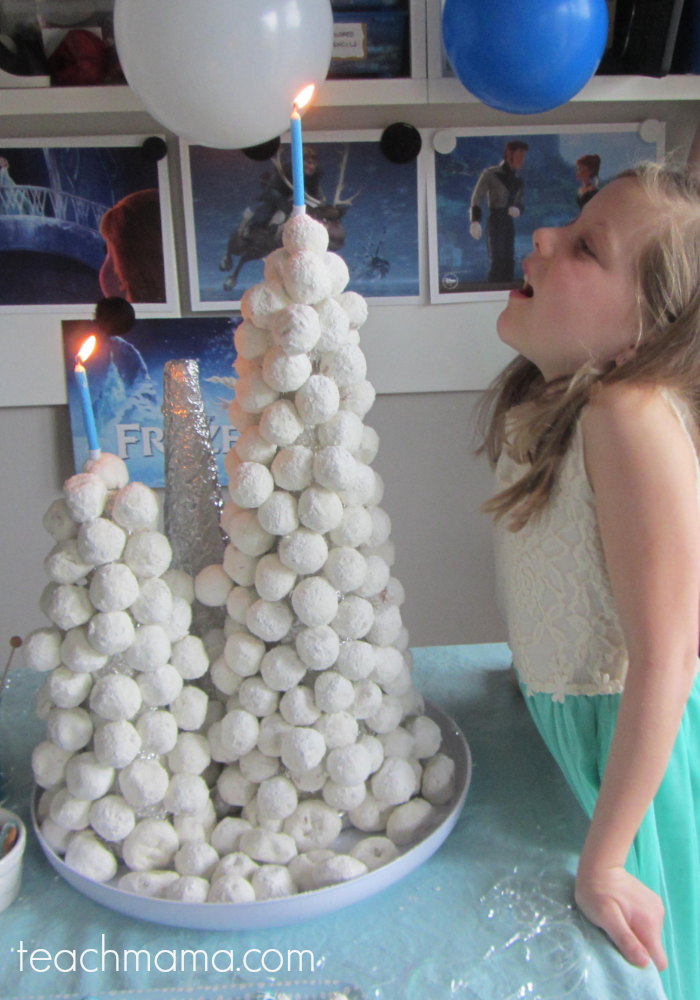 girl blowing out candle in snowball tower cake