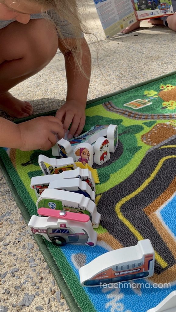 little girl playing on carpet with paw patrol figures