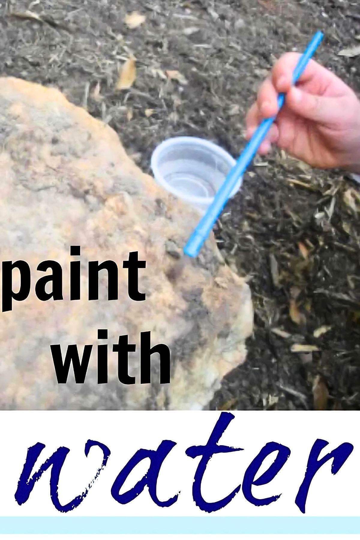 Child's hand using a brush to paint with water on a rock