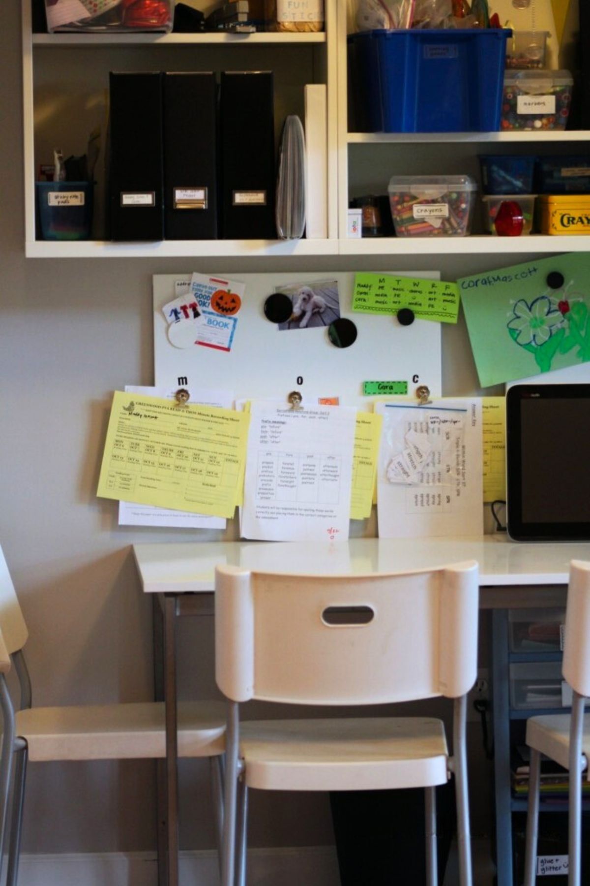 Kid's study table with magnetic whiteboard on the wall behind and cubbies above with school supplies in plastic tubs
