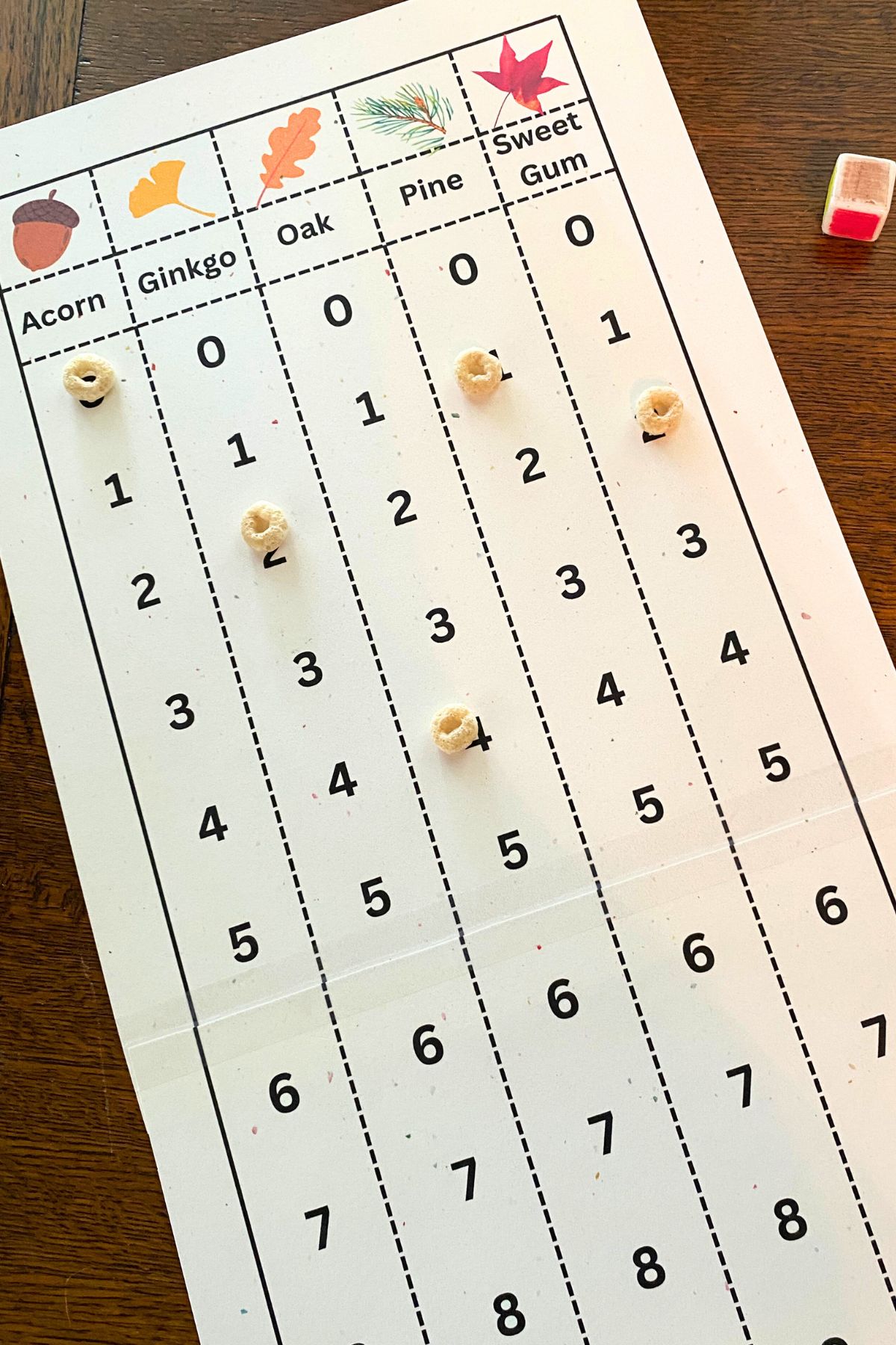 Ptined game board with cartoon acorn, ginkgo, oak, pine and sweet gum leaves at the top of five columns of numbers