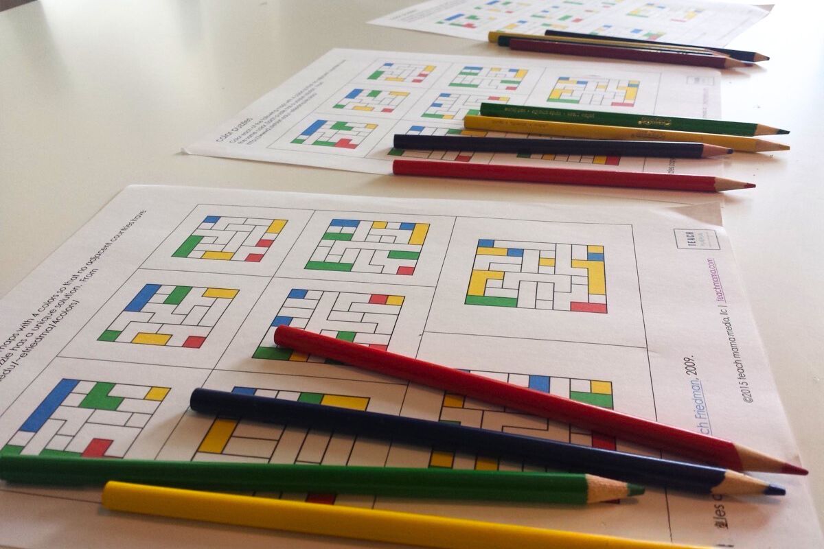 multiple color puzzles on a white table with colored pencils