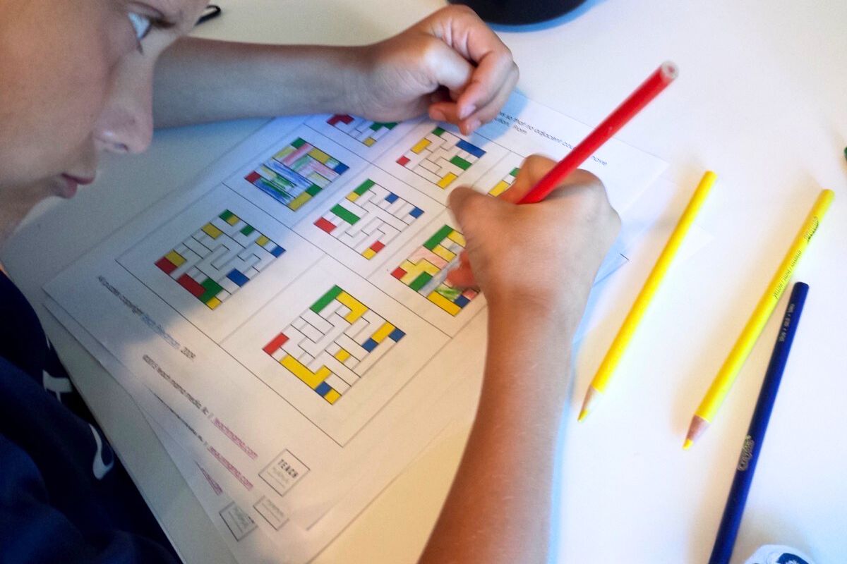 Boy working color puzzles with a red pencil