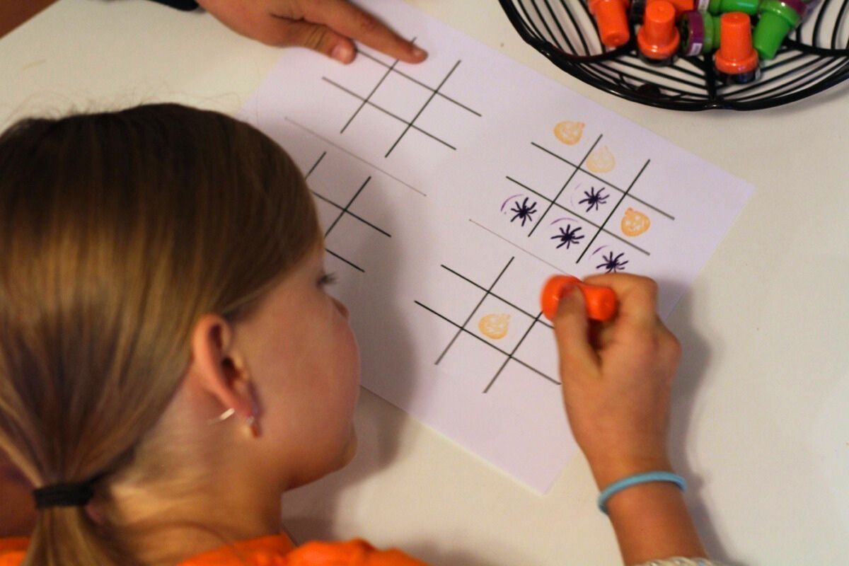 Girl stamping pumpkins and spiders on the tic-tac-toes board