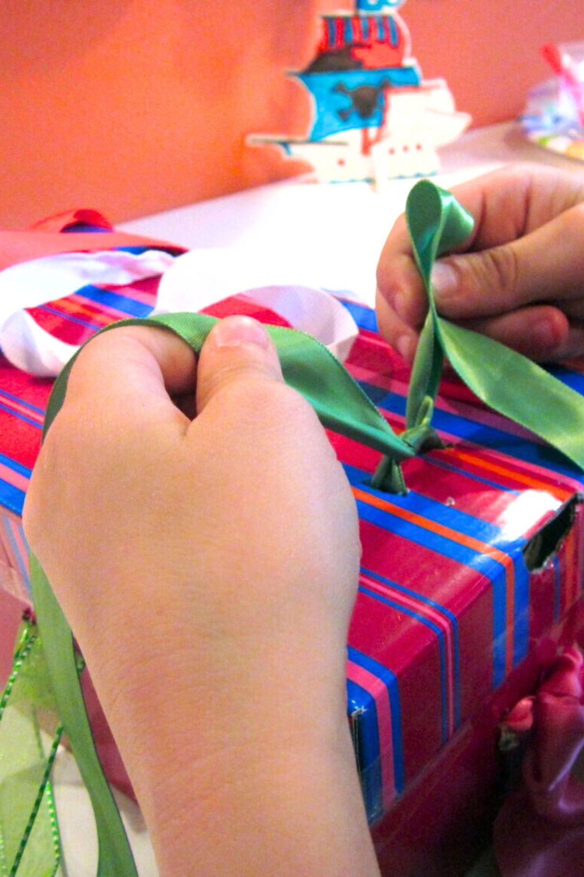 shoelace box 13 Hands tying laces on a shoe box wrapped in red and blue striped paper
