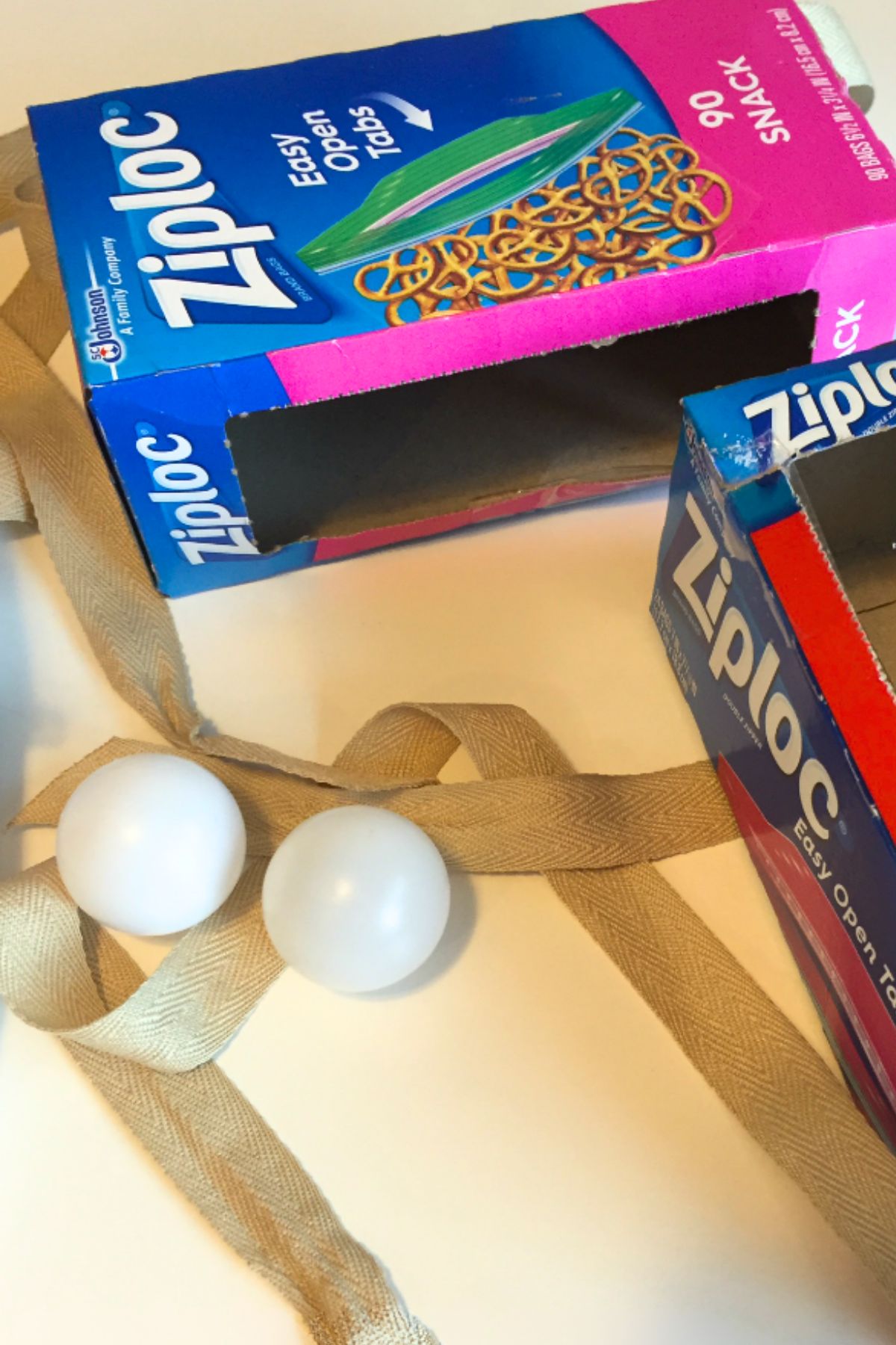 Ziplock baggie box with a cloth strap and two ping pong balls