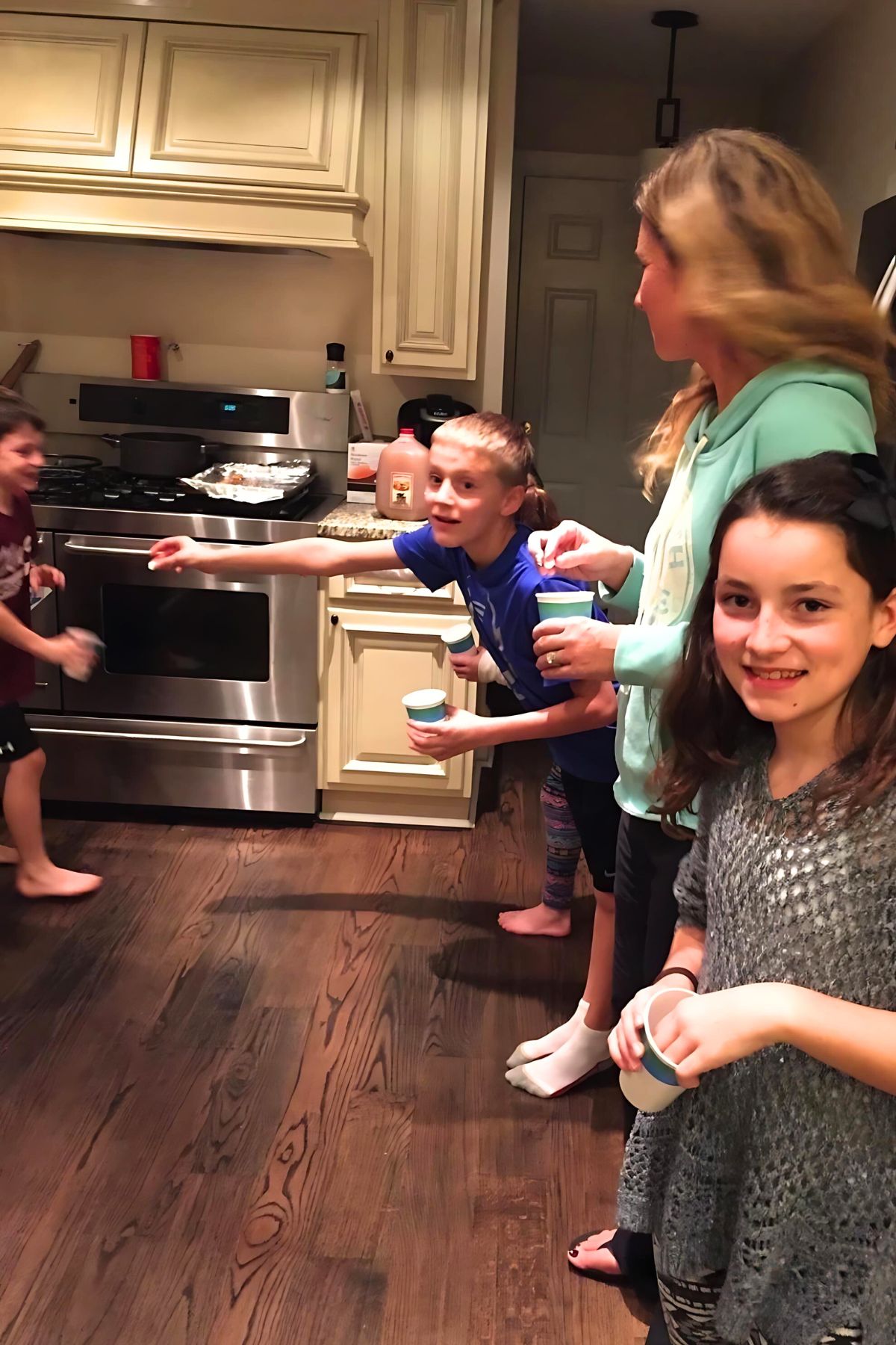 Adults and children standing in lines facing each other in a kitchen