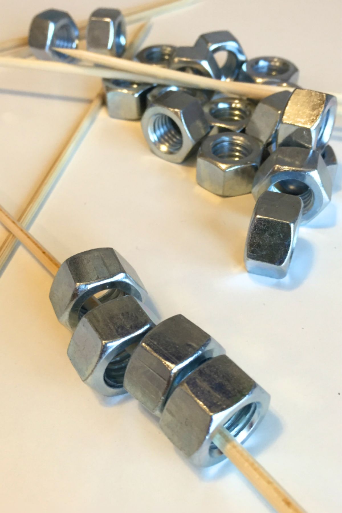 Steel hex nuts threaded onto a wooden skewer