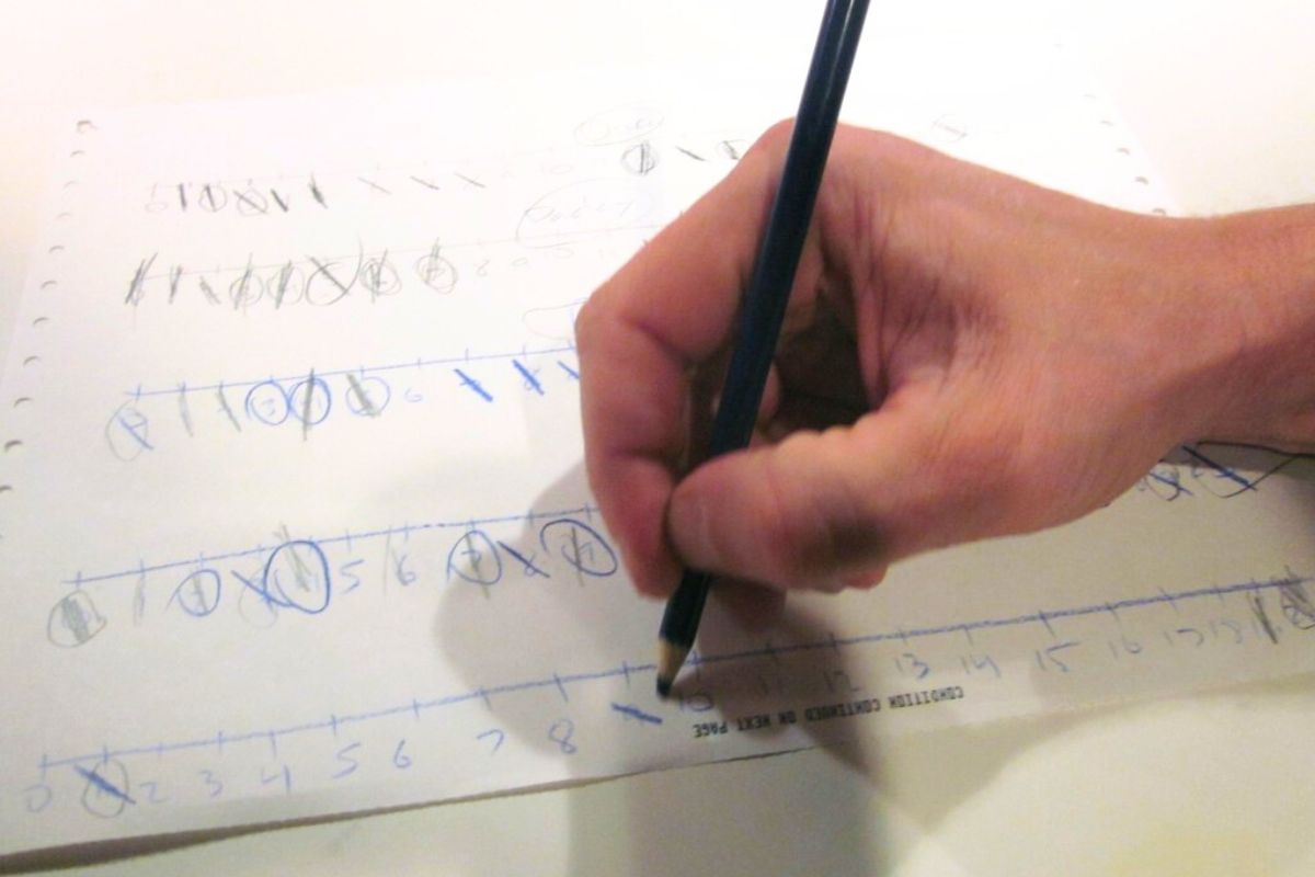 Close-up of hand marking numbers on a strike it out game sheet