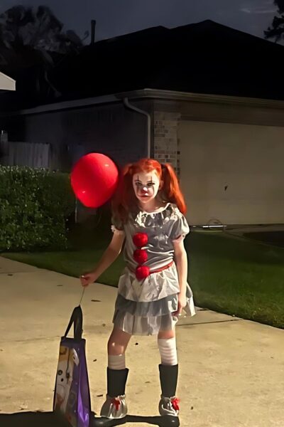Child dressed as a clown holding a red balloon
