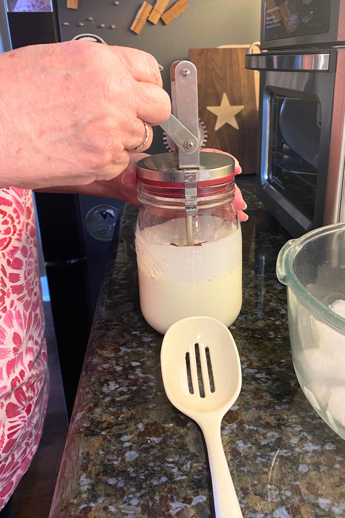 Hand turning a small butter churn set on top of a mason jar