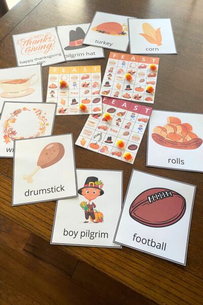 Colorful Thanksgiving-themed Bingo boards surrounded by Thanksgiving character cards on a wooden table