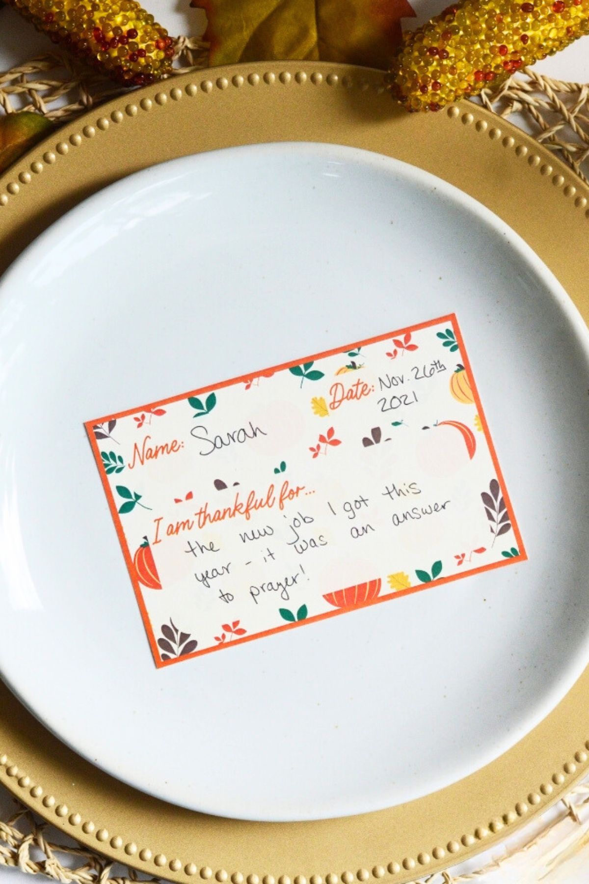 Printed place card on a gold-rimmed plate with a space for name, date and what the person is thankful for