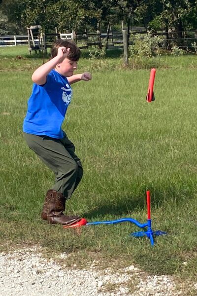 Child stomping on an air rocket pad with the red foam rocket in flight