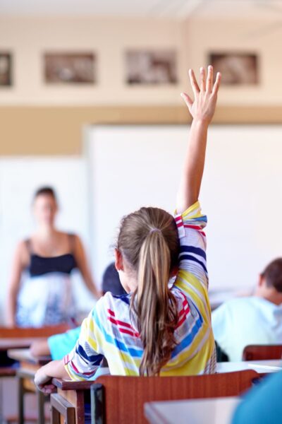 Girl in a classroom with her hand raised