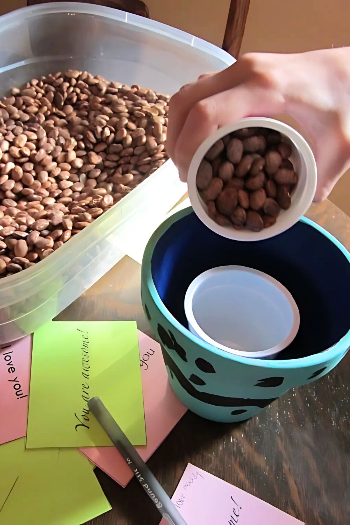 Child filling the painted pots with dry beans as ballast