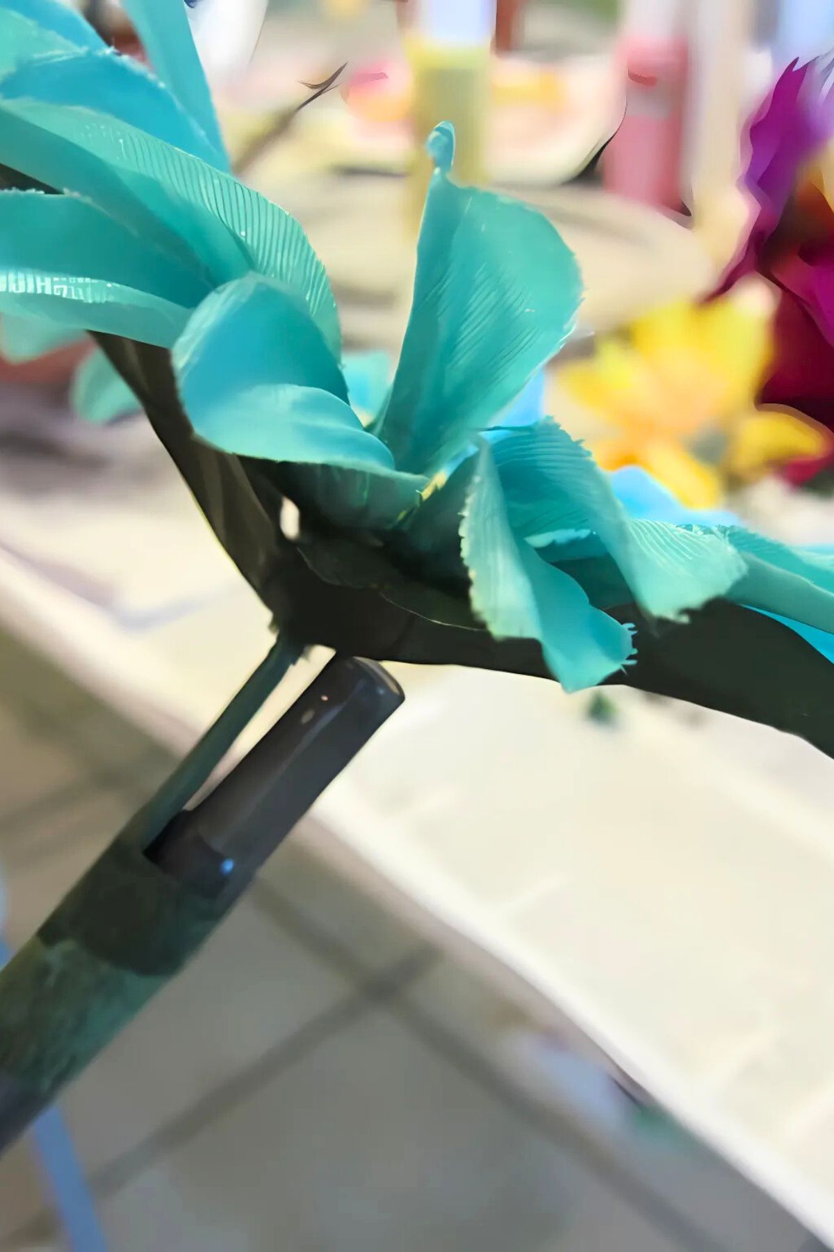 Blue silk flower attached to a writing pen with green floral tpe