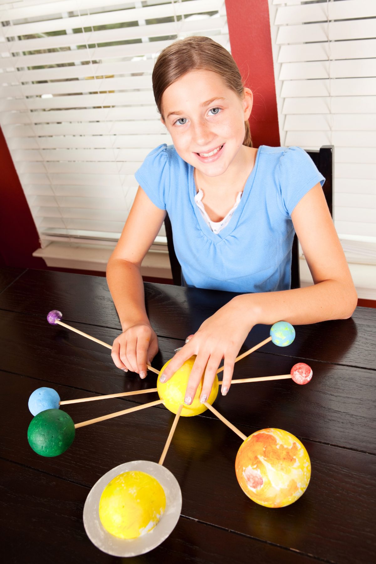 Girl sitting in front of a foam ball and stick solar system model