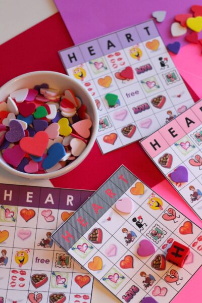 Heart Bingo cards printed on white cardstock and a bowl of foam hearts on a red tablecloth