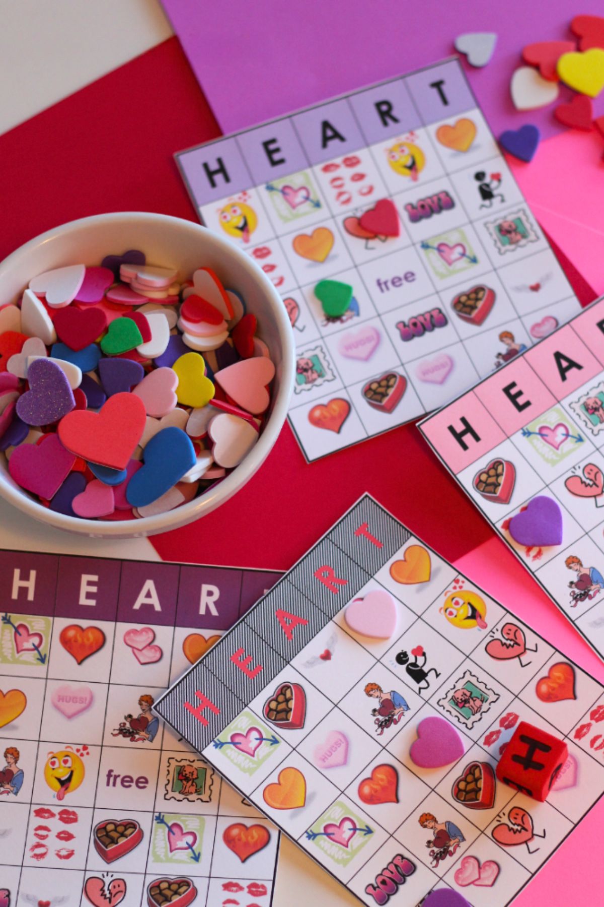 Heart Bingo cards printed on white cardstock and a bowl of foam hearts on a red tablecloth