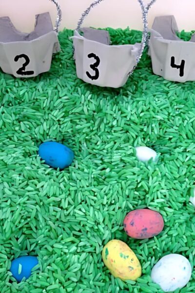Egg cartons cut to form small baskets and colorful candy eggs on green stained rice