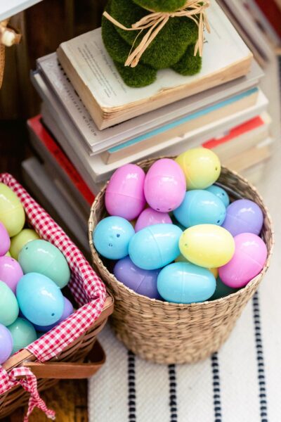 Pink, blue and yellow plastic Easter Eggs in a basket next to a stack of books