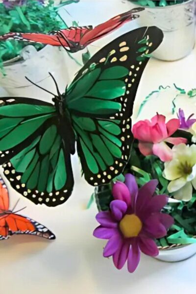 Bright green silk butterfly on an ink pen in a bucket with colorful silk flowers