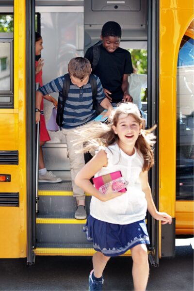 Happy kids getting off of a yellow school bus