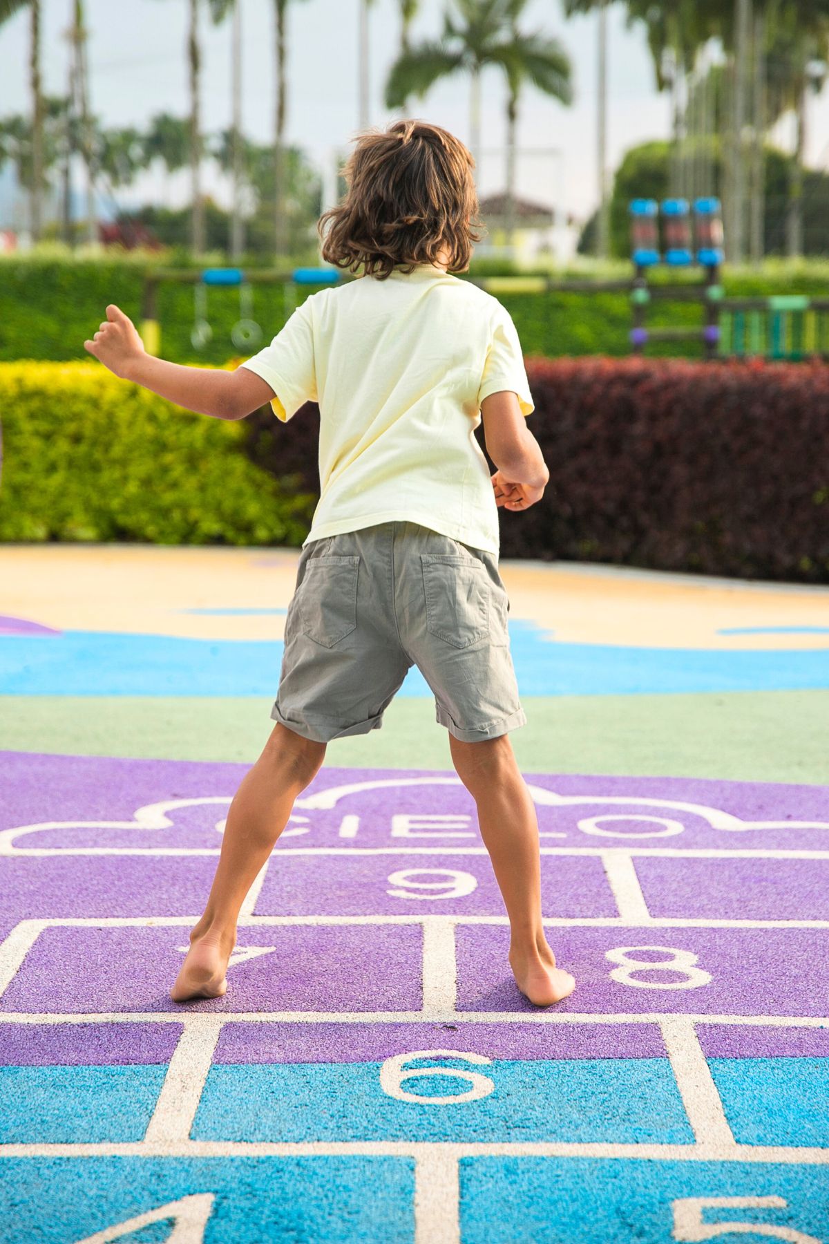 Child in a yellow short playing hopscotch